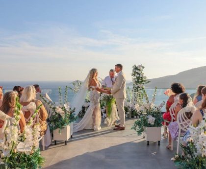 Elegant outdoor wedding ceremony with ocean view and floral decor.